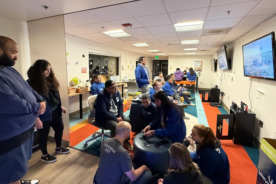Group of students and Residential Life staff gathered in a room playing cards, board games and video games